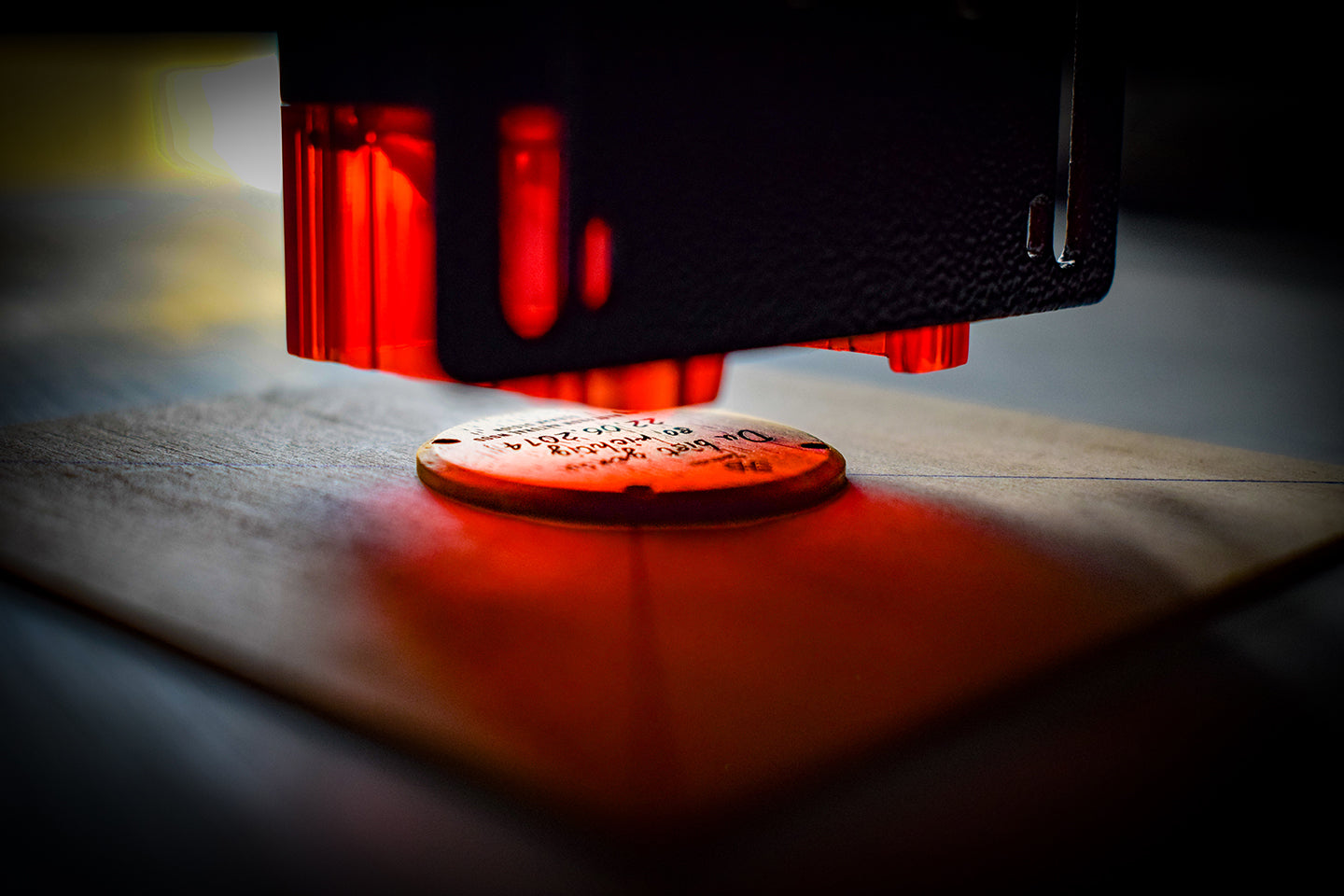 Lasergravurmaschine erstellt eine personalisierte Botschaft auf einer Zeitholz Uhr, Nahaufnahme mit rotem Lichteffekt.