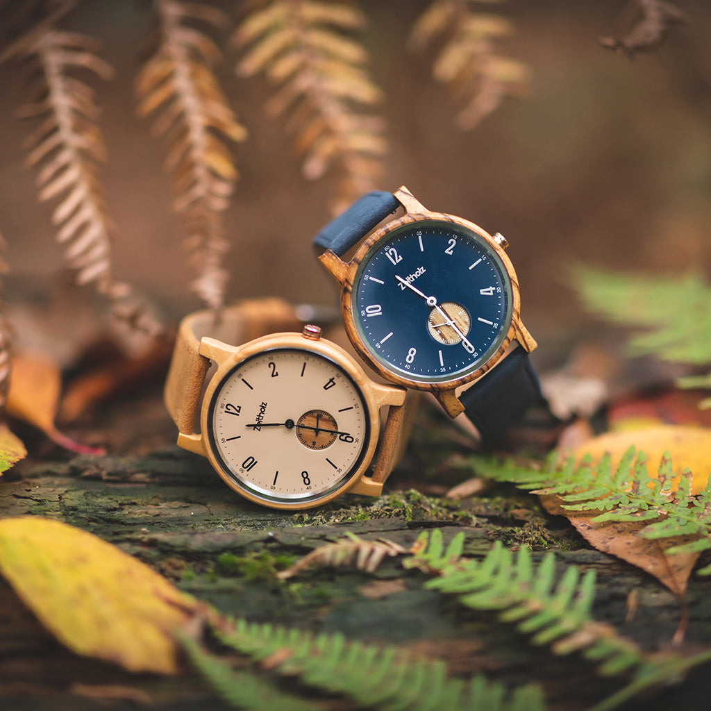 Zeitholz Armbanduhren aus Naturholz vor herbstlichem Laubhintergrund.